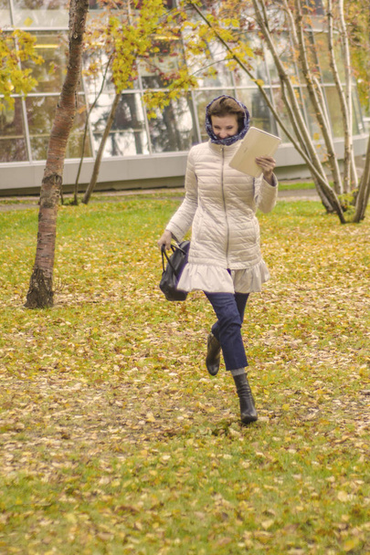 Beautiful European woman in autumn park. Beautiful european smiling woman runs through the autumn park. - Photo, image