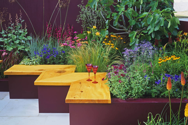 Farbenfrohe Bepflanzung im "Sommercocktail" und Sitzgelegenheiten in einem modernen Garten  - Foto, Bild