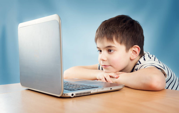 seven years old child sitting with a laptop at table - Photo, Image