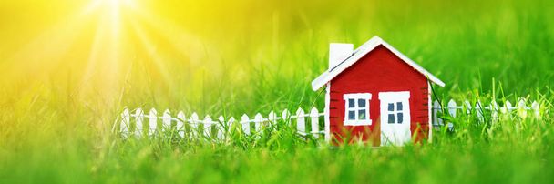 модель красного деревянного дома на траве в саду - Фото, изображение