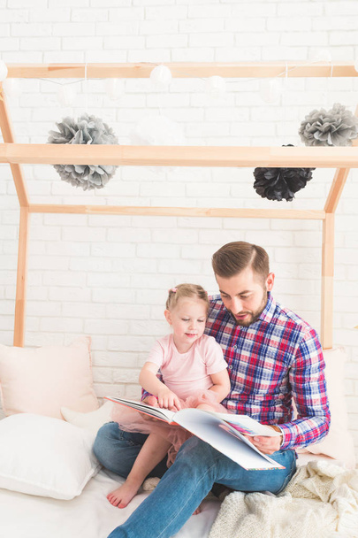 Dad and daughter sit together and read a book. - Foto, imagen