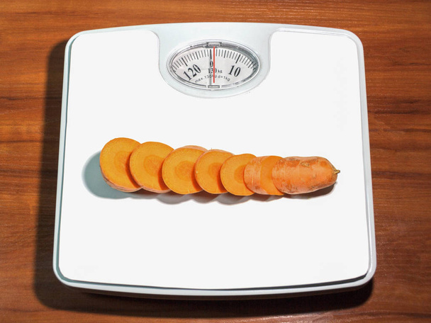 Sliced carrots on scales to measure human weight - Photo, Image