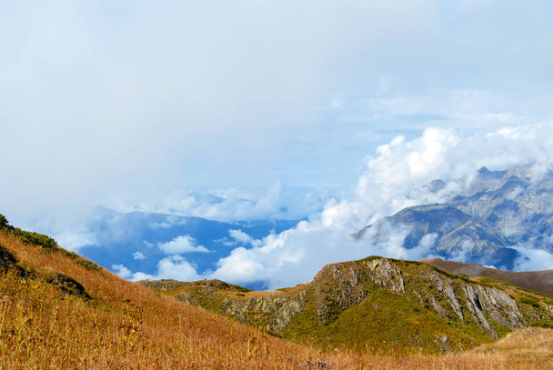 Outono paisagem montanhosa do Cáucaso com prados alpinos rochosos e distantes cadeias de montanhas na nuvem
 - Foto, Imagem