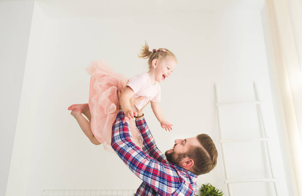 Cute little girl and her dad are having fun at home. - Фото, изображение