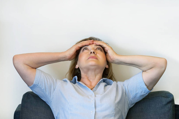 Bejaarde vrouw lijden aan hoofdpijn migraine pijn thuis. Gezondheidsprobleem, stress en depressie. Hoofd van de vrouwelijke bezit met hand. Begrip gezondheid. - Foto, afbeelding