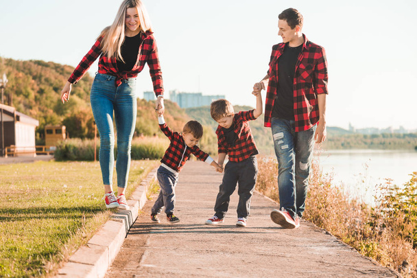 Молодая счастливая семья с детьми, развлекающимися на природе. Родители гуляют с детьми в парке
 - Фото, изображение