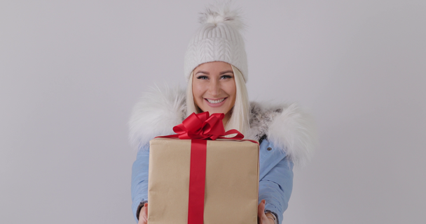 Blij verrast vrouw in winter bontjas, Holding aanwezig in haar handen, maakt een wens en krijgt van een doos van de gift. Witte achtergrond. - Video