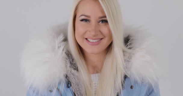 Ξανθιά γυναίκα στο γούνινο παλτό Ανυψούμενο Χιόνι στο studio σε λευκό φόντο, αργή κίνηση, 4k - Πλάνα, βίντεο
