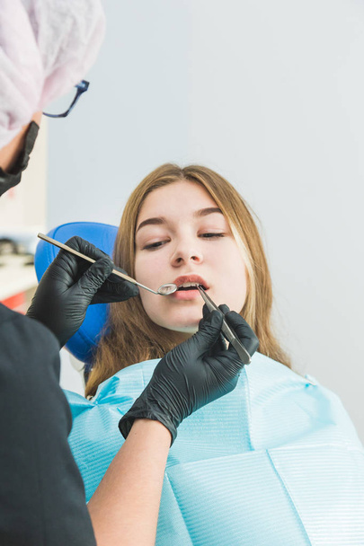 Dental clinic. Reception, examination of the patient. Teeth care. Young girl undergoes a dental examination by a dentist - Fotografie, Obrázek