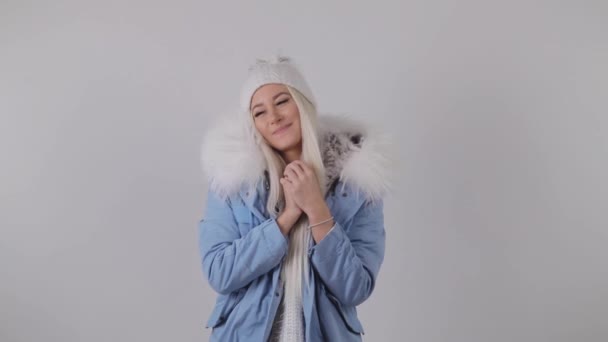 Ευτυχισμένος ξανθιά γυναίκα στο χειμερινό παλτό γούνα, παρόντες κρατώντας στα χέρια της, κάνει μια ευχή και παίρνει ένα κουτί δώρου. Λευκό φόντο. - Πλάνα, βίντεο