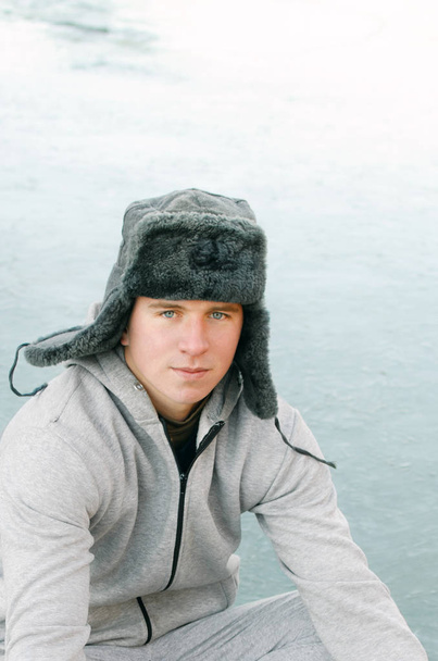 χειμώνα πορτρέτο ενός νεαρού άνδρα σε ένα γούνινο καπέλο με earflaps - Φωτογραφία, εικόνα