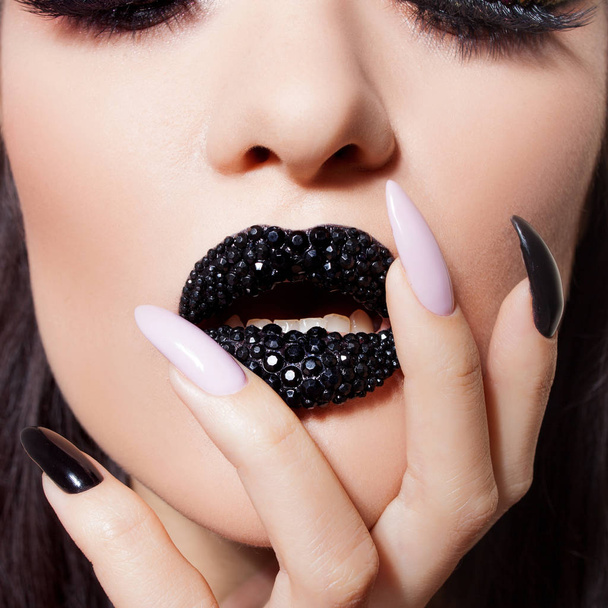 Black lips covered with rhinestones. Beautiful woman with Black lipstick on her lips and black and white manicure - Photo, image