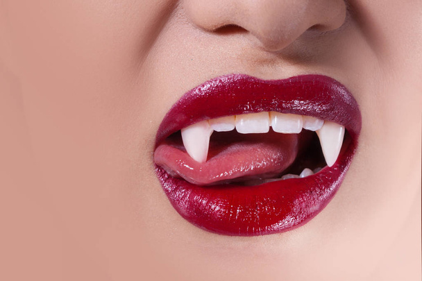 Sexy vampire. Women's lips with red lipstick. Tongue licking vampire fangs - Zdjęcie, obraz
