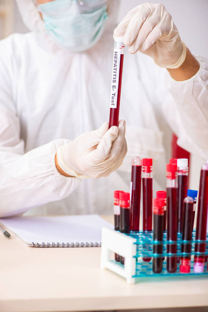 Молодой симпатичный лаборант тестирует образцы крови в больнице  - Фото, изображение