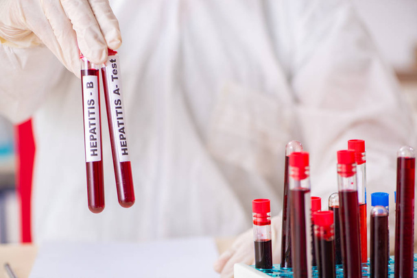 Jeune assistant de laboratoire beau tester des échantillons de sang à l'hôpital  - Photo, image