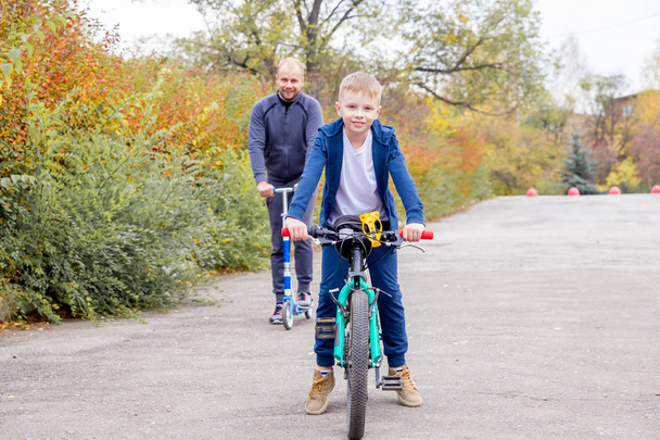 Father teaching his son to ride a bike in a park - Fotoğraf, Görsel