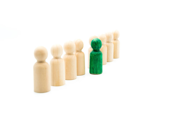 Figuras de madera en línea como equipo de negocios, con una figura verde destacándose de la multitud, aislada sobre fondo blanco. Imagen conceptual de ser diferente
 - Foto, imagen