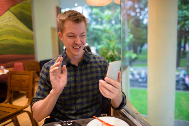 Молодой турист снимает видео с мобильного телефона в ресторане
 - Фото, изображение