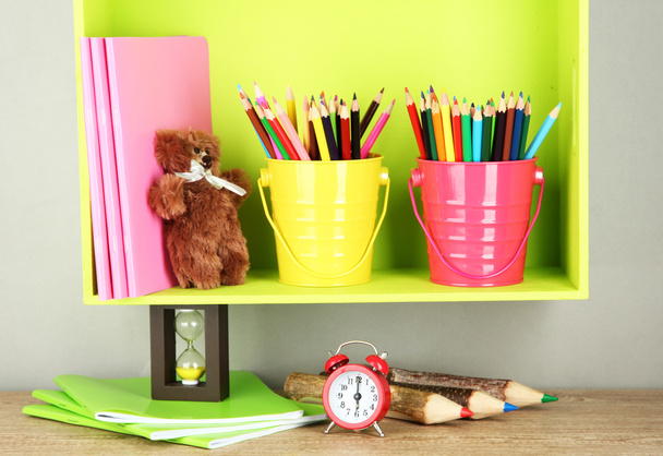 Colorful pencils in pails on shelf on beige background - Фото, изображение