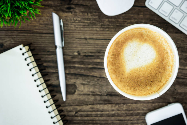 Un café con leche con leche de corazón de arte en la mesa de escritorio de madera marrón desde la vista superior y espacio para copiar. Piso con escritorio, negocio y concepto de valentine
. - Foto, Imagen