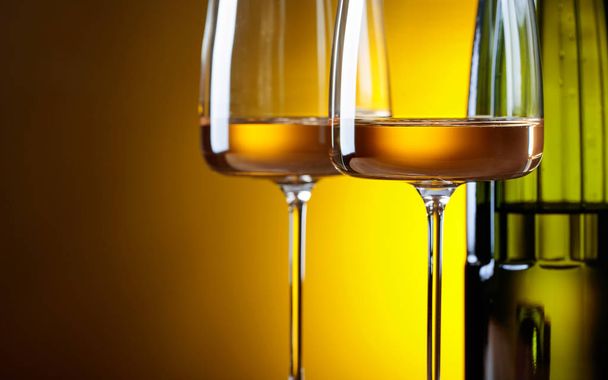 Bicchieri e bottiglia di vino bianco su fondo giallo. Focus selettivo
 . - Foto, immagini