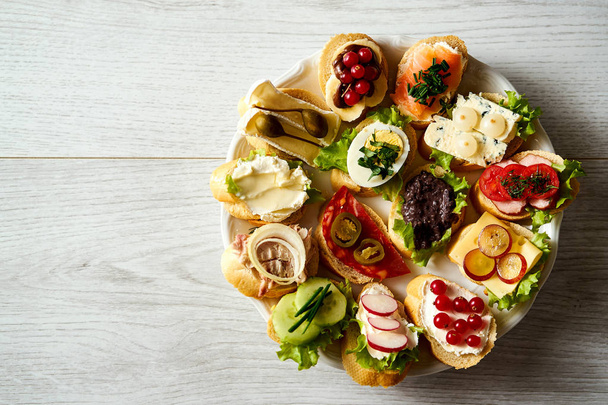top view of plate with colorful and healthy sandwiches or tapas on wooden table - Photo, Image