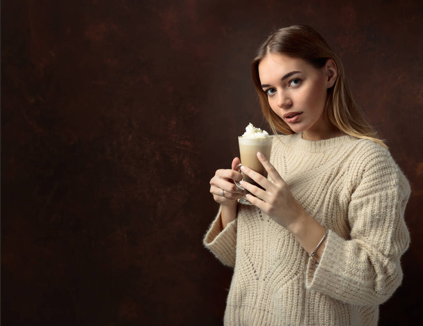 Jolie jeune femme avec du café irlandais. Belle blonde dans un pull tenant une tasse de café à la crème. Espace de copie
. - Photo, image