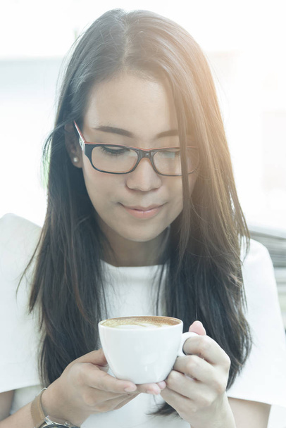 Schöne asiatische attraktive Frau hat halten und trinken einen Kaffee im Café am Morgen mit glücklicher und entspannter Zeit. - Foto, Bild