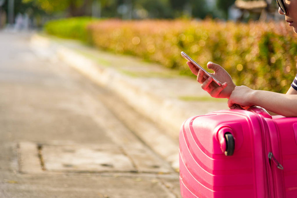 Красива мандрівник азіатка сидить на вулиці з великою рожевою сумкою для очікування служби таксиста ввечері з часом заходу сонця
. - Фото, зображення