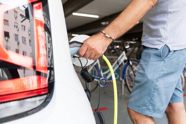 Hand holding an electric plug-in for charging electric car - Foto, imagen