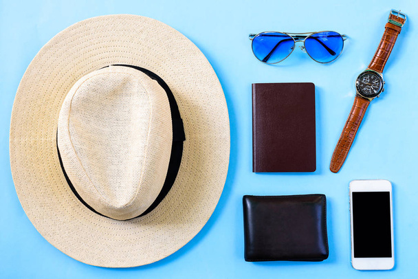 トップ表示夏の旅行計画のコンセプト白い帽子、青い眼鏡、電話、時計、空白のパスポートと青の背景に隔離された茶色の財布. - 写真・画像