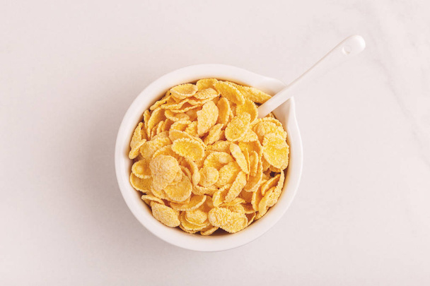 Crispy corn flakes in clay bowl on light marble background. Healthy cereals breakfast. Copy space - Foto, Bild