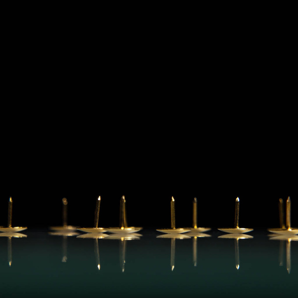 Sharp golden needles on a black background as a symbol of pain and danger. - 写真・画像