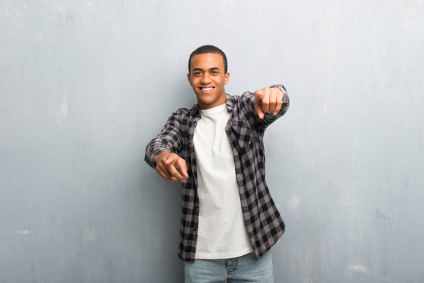 Young african american man with checkered shirt points finger at you while smiling - Photo, Image