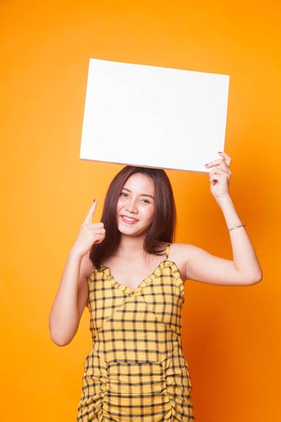 Jeune femme asiatique pointent vers signe blanc sur fond jaune
 - Photo, image