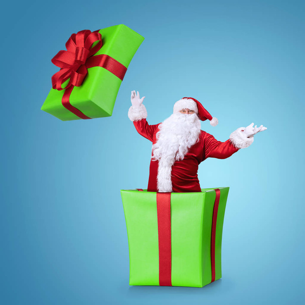 Happy Samta Claus hyppääminen ulos joulun laatikko eristetty sinisellä pohjalla kopioi tilaa
  - Valokuva, kuva
