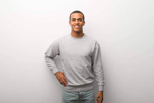 Uomo afroamericano su sfondo bianco muro in posa con le braccia all'anca e sorridente
 - Foto, immagini