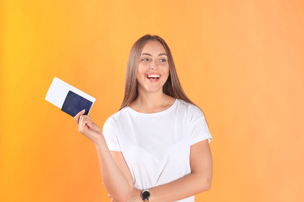 Excited young woman tourist standing isolated on yellow background holding passport with tickets. - Фото, зображення