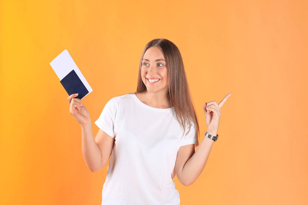 Excited young woman tourist standing isolated on yellow background holding passport with tickets. - Foto, immagini