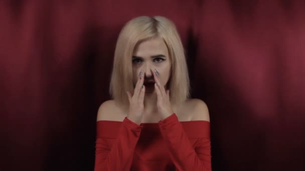 Happy beautiful girl surprised raises her hands to face against the background of red rocking fabric. - Materiał filmowy, wideo
