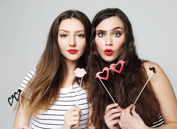 two stylish sexy  girls best friends holding paper party sticks  - Φωτογραφία, εικόνα
