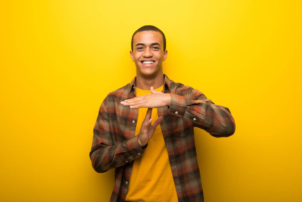 Молодий афроамериканець людиною на яскраві жовті фону прийняття зупинки жест з її боку зупинити акт - Фото, зображення
