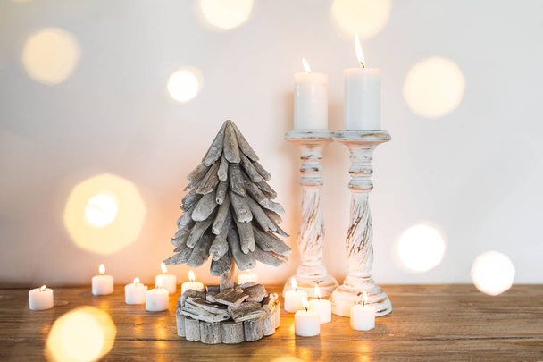 White wooden Decorated Christmas Tree with Candles and Golden blurred shiny lights around. Place for Text. Hand Made Festive Concept - Photo, Image