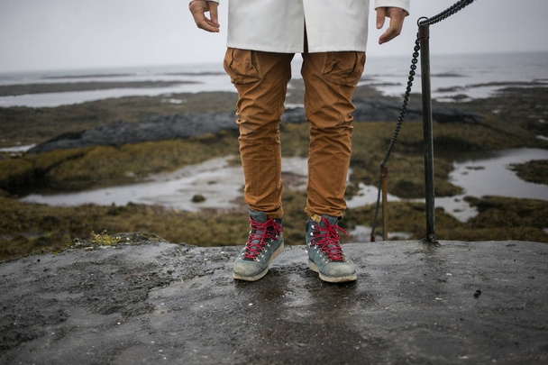 Tourist in white raincoat walks on iceland shore - Photo, image