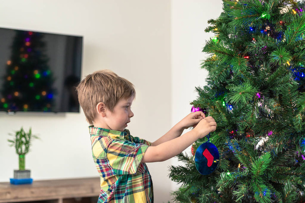 Cute australian boy decorating Christmas tree at home - Foto, afbeelding