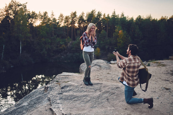 Young couple of tourists are exploring new places. Attractive young woman and handsome bearded man are spending time together on nature. Making proposal of marriage. - Foto, immagini