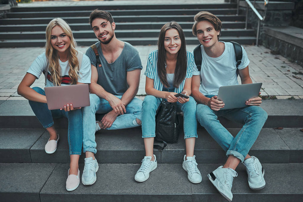 Group of young people are studying together in university. Students outdoors sitting on stairs. - Foto, imagen