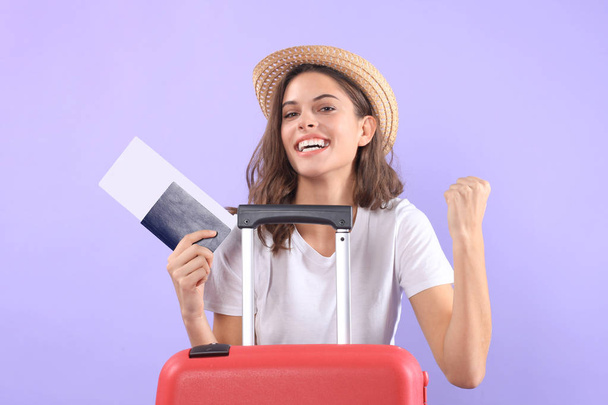 Young tourist girl in summer casual clothes, with sunglasses, red suitcase, passport isolated on purple background. - Фото, изображение