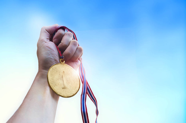 Athletic man hand holding golden coin medal. - Foto, Bild