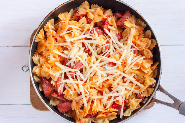 Step-by-step cooking pasta with sausage in tomato sauce with cheese, step 6 - adding cheese, selective focus, top view - Foto, immagini